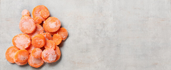 Frozen carrot slices on grey background with space for text