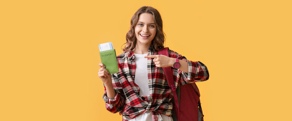 Beautiful female tourist with passport and tickets on yellow background