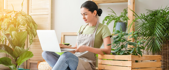 Young female gardener with laptop at home