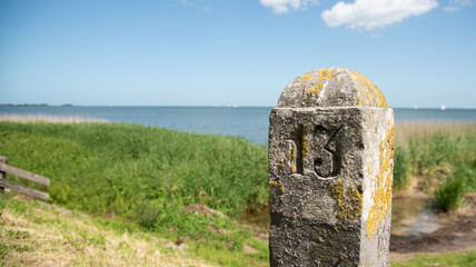Enkhuizen, Netherlands. June 2022. Old boundary pole on the dike near Enkhuizen.