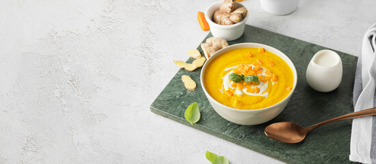 Bowl of tasty carrot cream soup on light background with space for text - obrazy, fototapety, plakaty