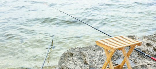 Fototapeta na wymiar Stool and fishing rod on river bank