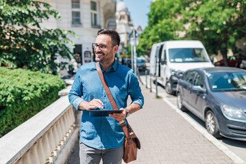 Obraz premium Happy executive using digital tablet while walking on sidewalk during sunny day