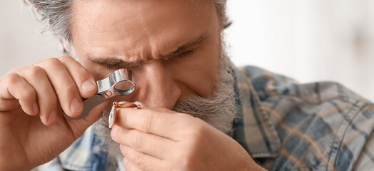 Senior jeweler examining adornment in workshop, closeup