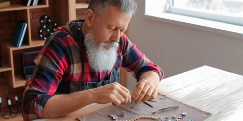 Mature jeweller examining gemstone in workshop