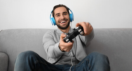 Young man playing video games at home - obrazy, fototapety, plakaty