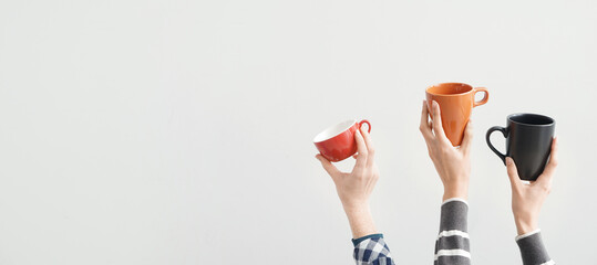 Female hands holding cups on light background with space for text