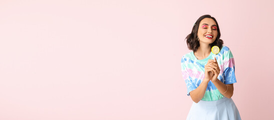 Beautiful young woman with lollipop on pink background with space for text