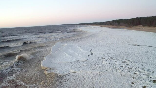 Dramatic low altitude drone flight above frozen sea. Next to empty coast line.