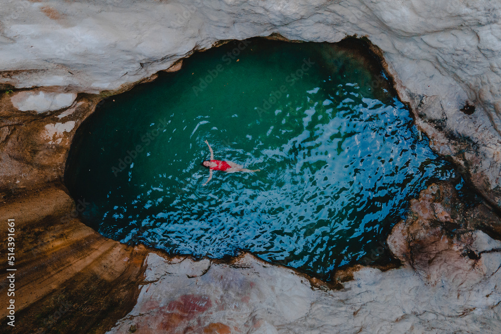 Sticker overhead view of dimosari waterfall lake with happy woman floating on the back