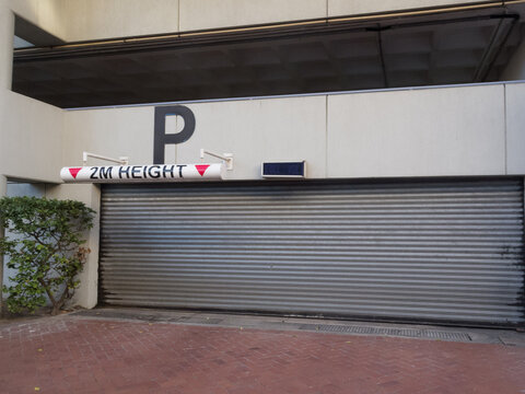 parking garage entrance with closed metal garage door and maximum height restriction sign to a public building