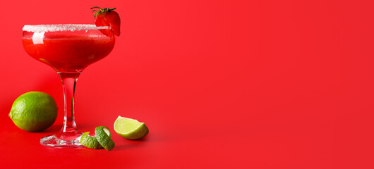 Glass of strawberry daiquiri cocktail and lime on red background with space for text
