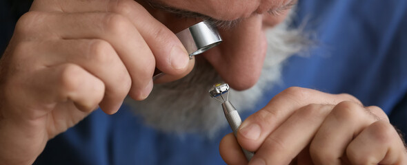 Senior jeweler examining gemstone in workshop, closeup