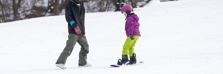Fototapeta na wymiar Ski Resort Father Teaching Little Daughter Snowboarding