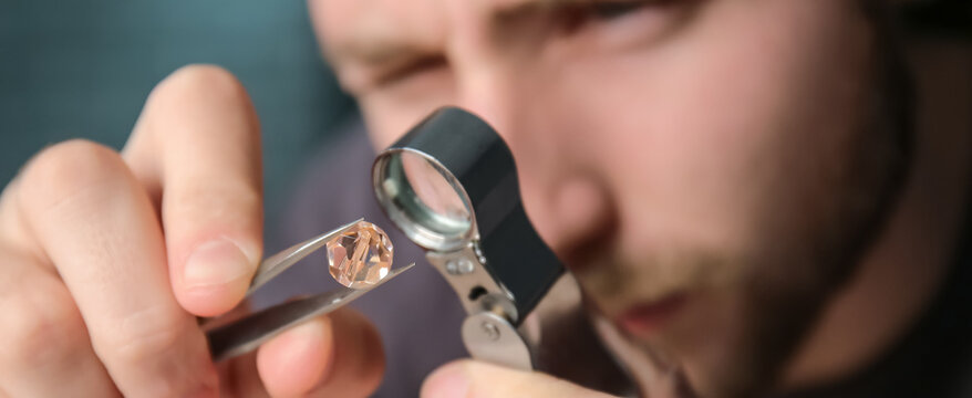 Jeweler examining gemstone in workshop, closeup
