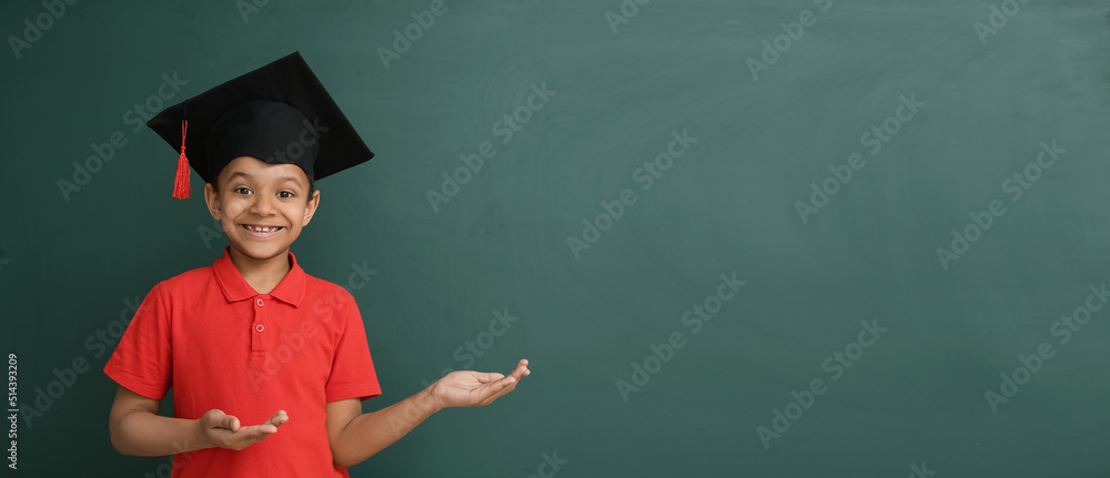 Wall mural Little African-American boy in graduation hat on color background with space for text