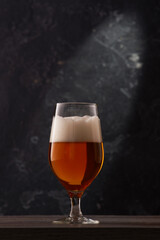 Tulip glass of beer on black background.