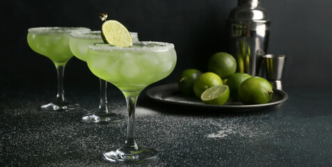 Glasses of tasty daiquiri cocktail on dark background
