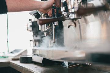 Coffee machine in steam, barista preparing coffee at cafe