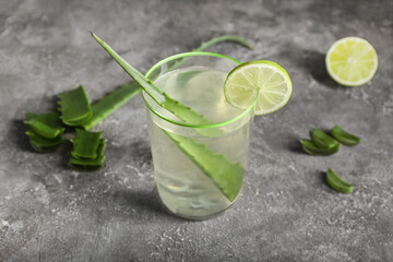 Glass of aloe juice with leaf and lime on grunge background