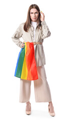 Portrait of stylish young transgender woman with LGBT flag on white background