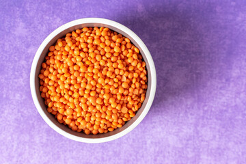 Stylish photo of dried red lentils on purple background 