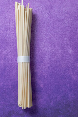 a bundle of uncooked udon noodles for Japanese cooking on a purple background with copy space