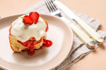 Plate with strawberry cinnamon roll and cream on beige background, closeup