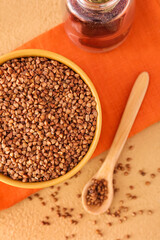 Bowl with buckwheat seeds on color table