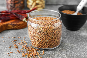 Glass jar with buckwheat grains on grunge table