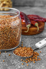 Spoon and glass jar with buckwheat grains on grunge table
