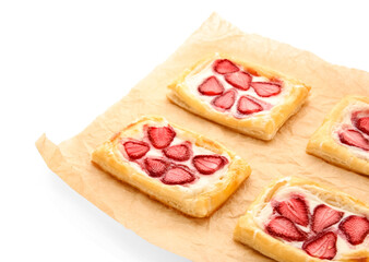 Parchment paper with strawberry puff pastries on white background