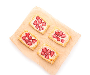 Parchment paper with strawberry puff pastries on white background