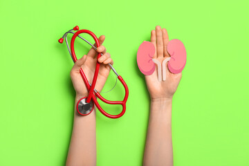 Woman with stethoscope and paper kidneys on green background