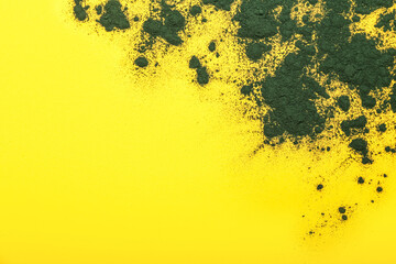 Green spirulina powder on yellow background