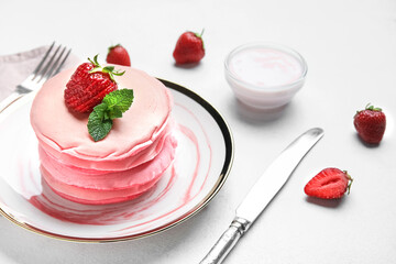 Plate of tasty pink pancakes with strawberry on table