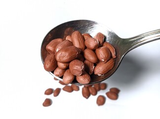 Close up. brown peanuts with stainless steel spoon isolated on white background