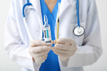 Female doctor with monkeypox vaccine and syringe on light background, closeup
