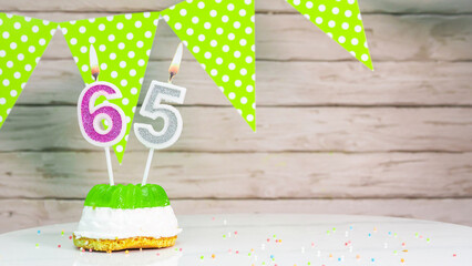 Beautiful festive background with the number 65  with a cake and lit candles, space saving for any...