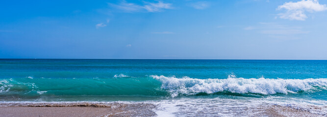 Panorama of a turquoise wave with white foam on a sandy ocean beach in Melbourne Beach, Florida