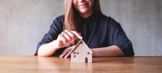 Closeup image of a woman holding and showing wooden house model