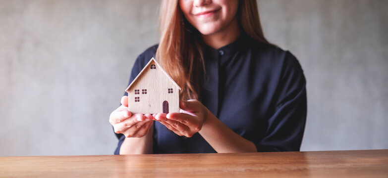 Closeup image of a young woman holding a wooden house model