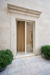 Fototapeta na wymiar Beige elegant front door with glass at the beige stone wall