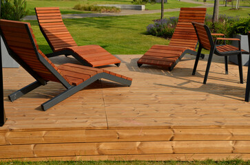 rocking chair on the pavement under the trees in the square. wooden deck chairs made of tropical...