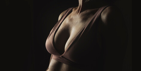 Seductive sexy female breasts in a bra on a dark background