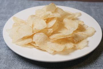 Bowl with tasty potato chips on wooden background .
