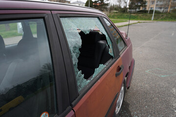 Car robbery on quiet street concept, broken rear window by burglar to get in the car and steal valuables inside