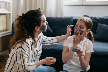 mother and daughter applying cosmetic clay face mask at home