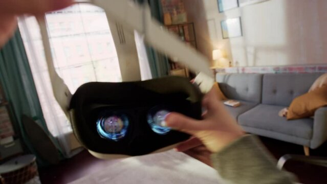POV of a Person Picking Up and Putting On Virtual Reality Headset Plays Video Game at Home. The Living Room Enters into Futuristic 3D Internet Metaverse World Full with Digital Avatars