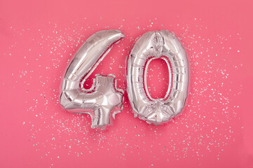 Silver balloon number 40 fourty shape sparkles scattered randomly on juicy pink background. Silver...